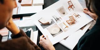 Over the shoulder shot of two interior designers viewing a furniture mood board