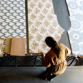 Seen from above, a craftswoman creates mosaic panels for the suites, with peacock, peaks, scallop and circle patterns.