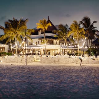 Glowing beach restaurant at night, viewed from across the water