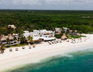 Aerial view of Maroma and its white pristine beach with thatched parasols, dividing the aquamarine sea from the lush land.