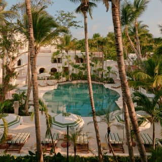 A ring of palms creates an oasis feel at Maroma's pool, which sits like a turquoise jewel in cream stone, seen from above.