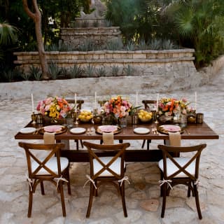 The sculpture of Chac Mool, reclining on a stone plinth, presides over a table ready for an intimate celebration on the stone courtyard.