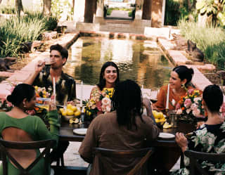 View over a table, where friends enjoy an exclusive celebration, along the pretty Ranas Fountain to the entrance and the sea.