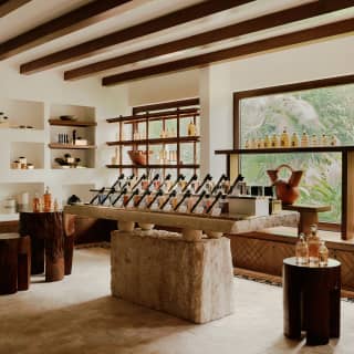 Neat lines of bottles rest on a large stone plinth in the spa showroom, where products fill wall alcoves and window displays.