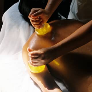 A member of staff at the Maroma Spa by Guerlin applies hot glass spheres to the back of a male guest during a muscle massage.