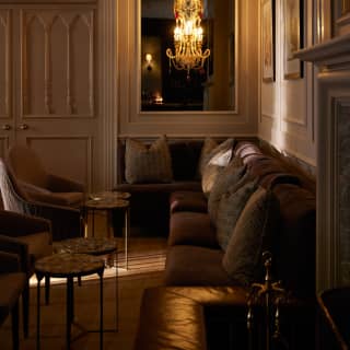 Bulbs in a mirror chandelier glow in the low-lit Planet Bar, where sofas and side tables carve a cosy nook in the grandeur.