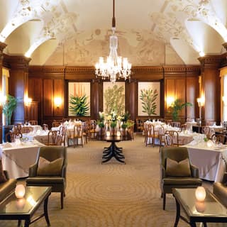 Double-height restaurant with wood-panelled walls and central chandelier