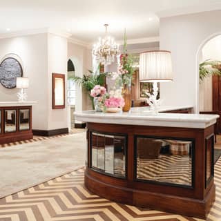 Bright lamplit hotel lobby with gleaming wooden desks with mirror insets