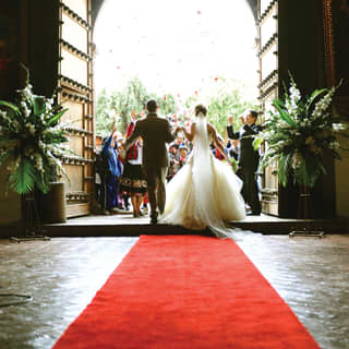 Newly married couple stepping out to applause from a group of guests
