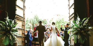 Newly married couple stepping out to applause from a group of guests