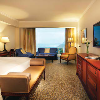 Sunny ocean views from a full-length window, just beyond a junior suite’s sofa and armchairs