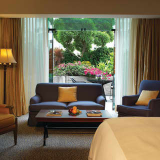 The open glass doors of a garden suite reveal the colours of the gardens beyond