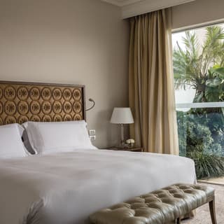 King-size pillowy bed beside a glass wall overlooking an outdoor plunge pool