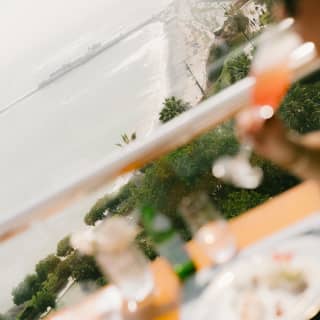 Angled image of a guest sipping a tall cocktail in soft-focus foreground, overlooking the dramatic coast of Lima.