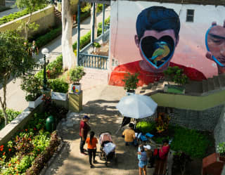 People gather to look at a mural of a bird inside a heart covering a boy's face, seen from above in the district of Barranco.