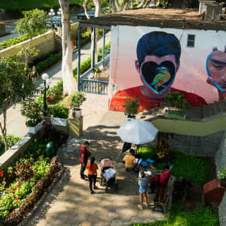 People gather to look at a mural of a bird inside a heart covering a boy's face, seen from above in the district of Barranco.