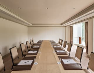 View down the central table in the Directorio room, with twelve chairs and place settings with paper and water glasses.