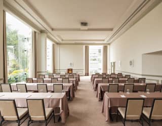 Ten beige-clothed tables divided into two columns and each seating four chairs face the front of the Salón Park venue.