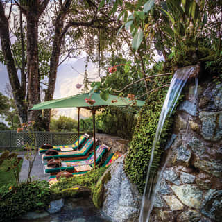 Rocky waterfall feature next to a row of sunbeds with colourful blankets