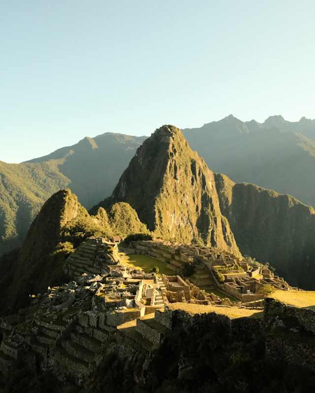 Sunshine illuminates the ancient ruins of Machu Picchu, cradled between the verdant peaks of Huchuy Picchu and Huayna Picchu.