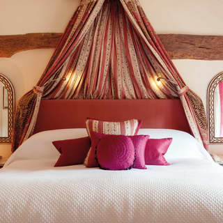 Pillowy bed flanked by two arched mirrors with an assortment of pink cushions