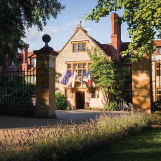 The evening sun gives a honey glow to the Cotswold stone hotel where the Union Flag, French Tricolour and EU stars fly