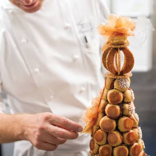 Chef Benoit Blin in chef whites building a praline dessert