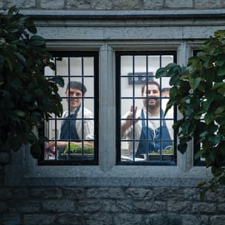 Two smiling chefs viewed through a medieval-style window