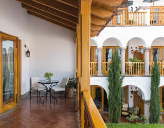 Spacious hotel room balcony with a seating area overlooking a garden courtyard