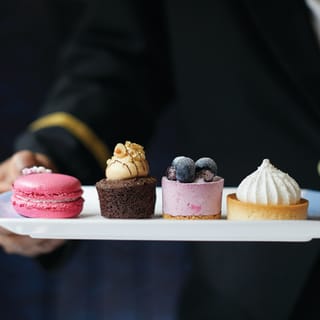 Afternoon tea platter, including a macaron, chocolate cake and lemon meringue pie