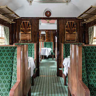 Wood panelled seats, upholstered in green geometric patterned fabrics gives a sense of luxury to this carriage interior