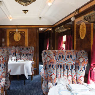 Vintage wood-panelled train carriage with liberty print chairs and formal dining tables
