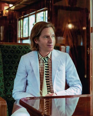 Filmmaker Wes Anderson sits at a French polished table in an art deco carriage and observes the world through the window