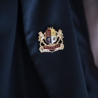 Close-up of a silver lapel badge design of the Belmond British Pullman emblem