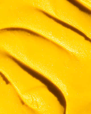 Close-up of unctuous mango-hued gelato, rippled and glossy in the sunshine.