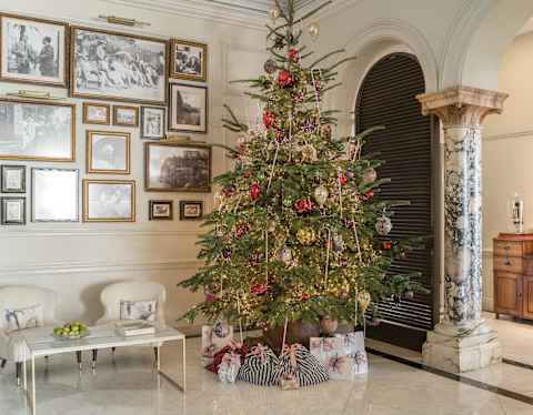 A tall Christmas tree, with baubles and tinsel in red and gold, creates a true festive splash in the white marble lobby.