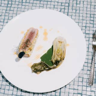 Crusted Carloforte tuna with fennel, cream of Swiss chard and seawater emulsion served at Éntu e Mari on a tiled table top.
