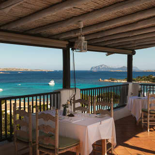 On La Terrasse's terrace, a table for four claims a spectacular view of sapphire waters with three boats and island contours.