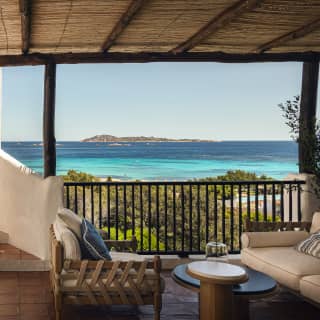 Steps from an upper terrace climb down to a lower one, where two sofas beneath a rattan shade enjoy extraordinary sea views.