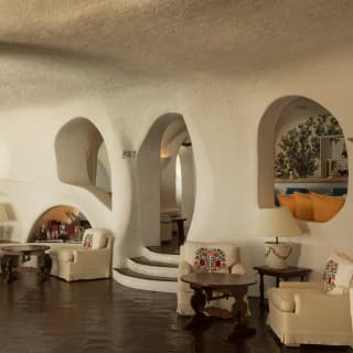 In a view of the lobby, two pairs of chairs sit in curves created by walls, seen past a pillar adorned with tree-shaped art.