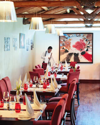 Waiter laying a table in an elegant restaurant with red soft furnishings