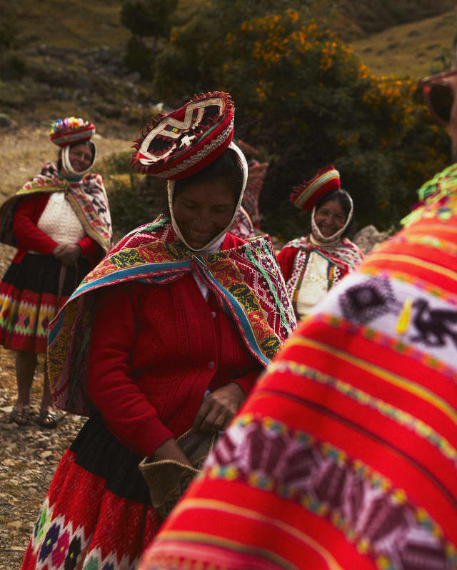 Angled image of three local women wearing tilted Montera hats and brightly woven Manta shawls over Jobona jackets for warmth.