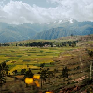 Behind a patchwork of green fields, the Andes range creates a dramatic backdrop with snow-capped summits, peaks and plateaus.