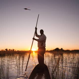 Guests enjoy a sunset canoe expedition in the Botswana wetlands