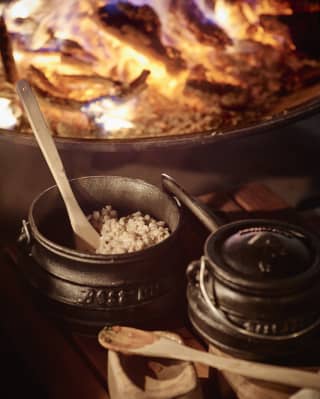 Pots of ingredients, delicate wooden spoons and cooking pots on a wooden kitchen worktop