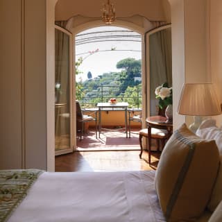 View from across a pillowy bed of a sun-splashed balcony beyond
