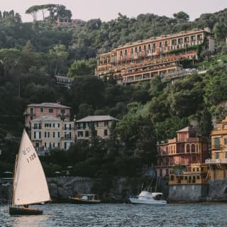 Sailing boat bobbing on the waves by the coastline with Splendido in the background