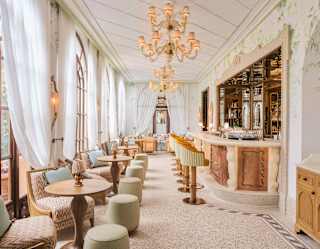 Lounge chairs and sage stools line a wall of windows opposite a bar in Baratta Sedici, which shines with Portofino glamour.