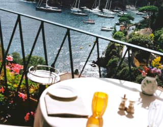 Angled view of the blue Baia Cannone, with boats lined along the headland, seen from a sunny table at La Terrazza restaurant.