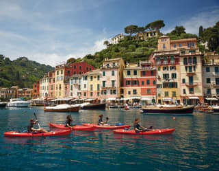 Guests in four vibrant red kayaks sailing across Portofino harbour